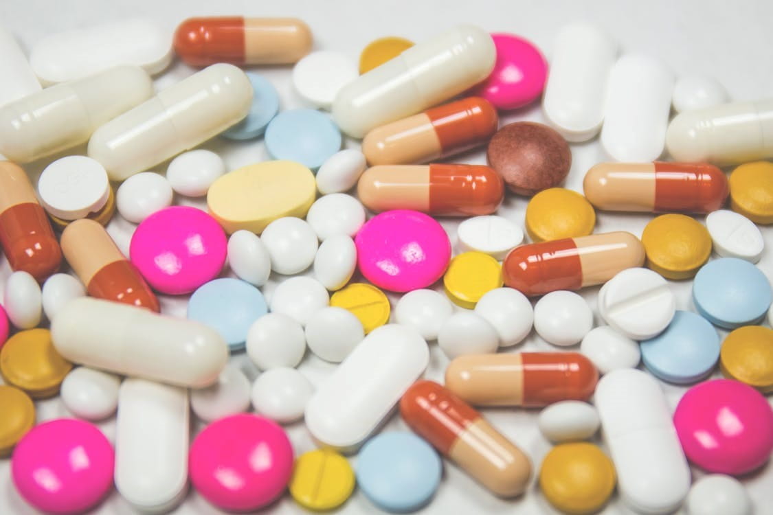 Pile of white, pink, and brown oblong and round medication tablets