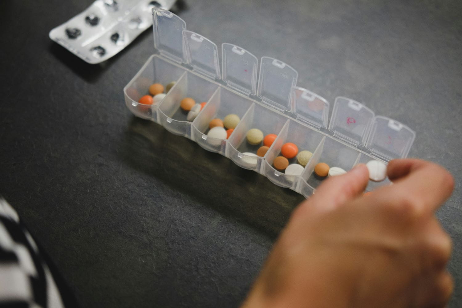 A closeup of a daily pill organizer, with several different pills in each section
