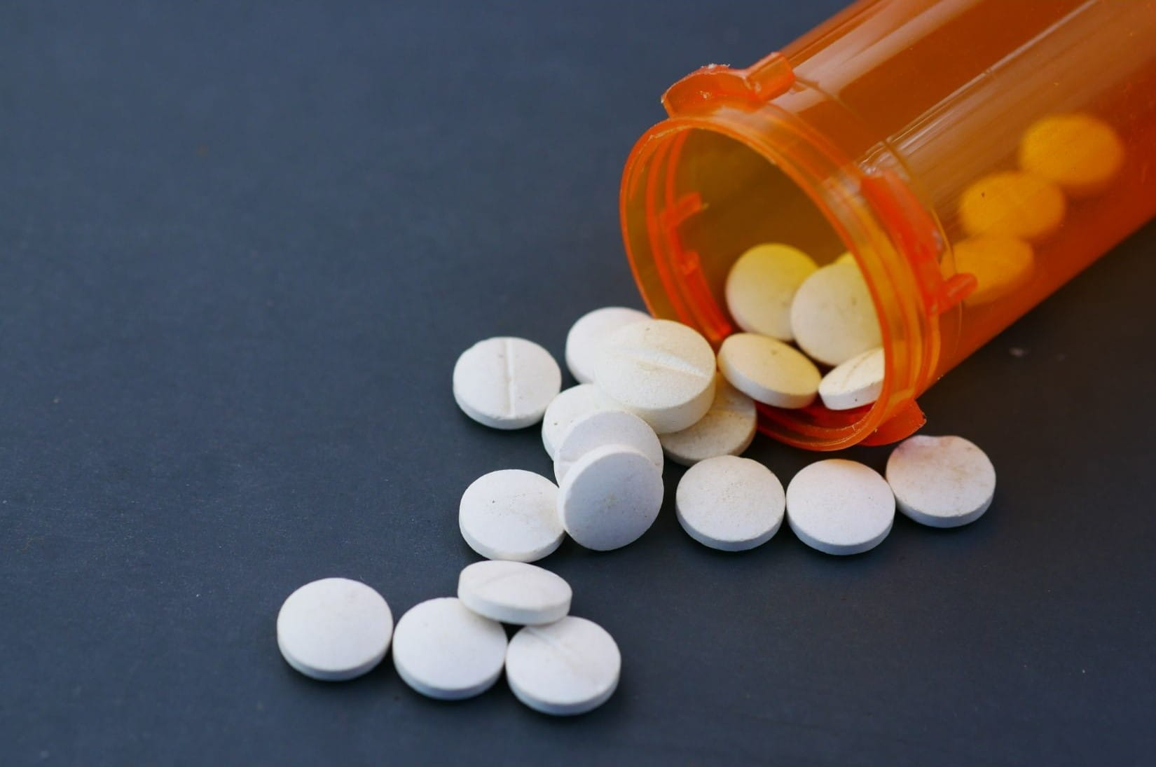 Prescription pill bottle with pills spilling out. 