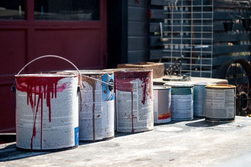 Several used paint cans sitting on the ground