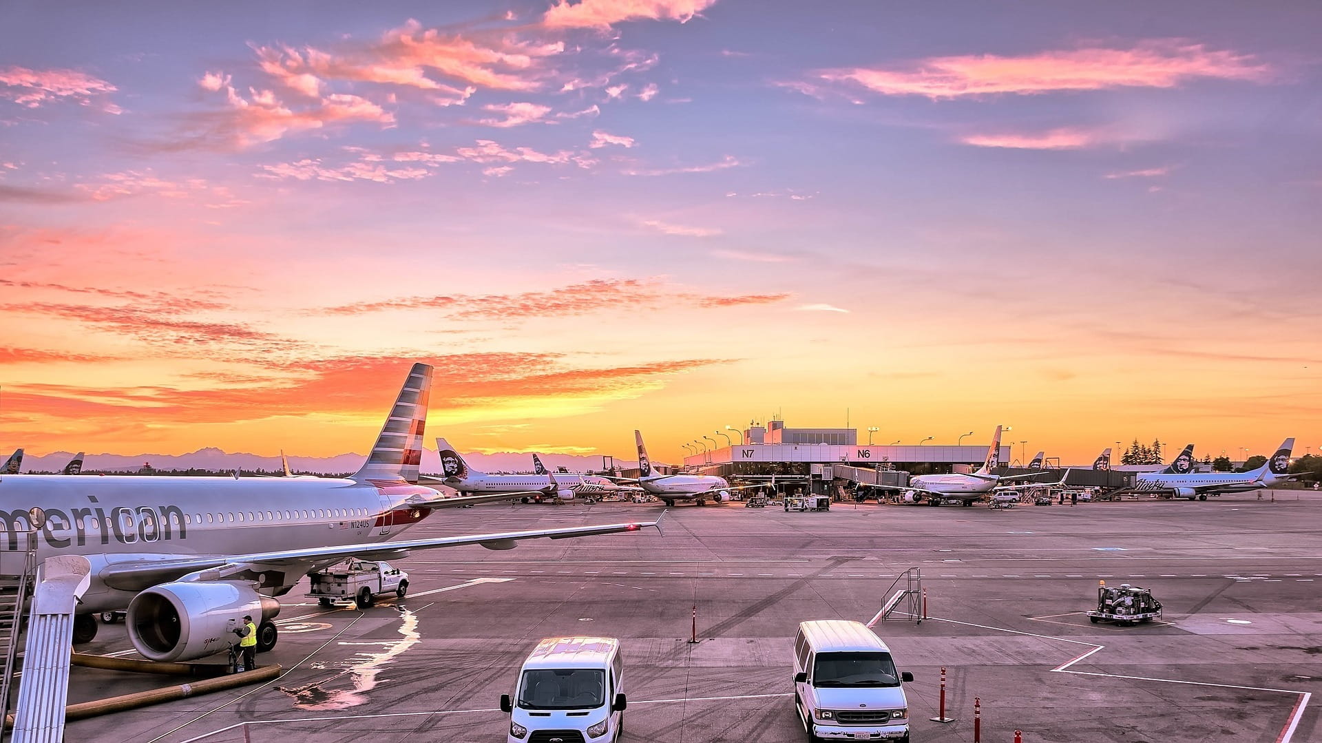 Airplanes on a tarmac with a sunset in the back.
