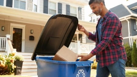 Person placing cardboard into recycling bin part of Feet on the Street program in Washtenaw County