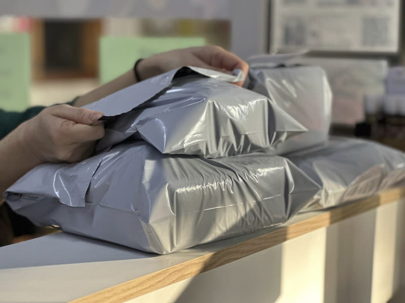 Someone adjusting a stack of mail boxes with plastic packaging.