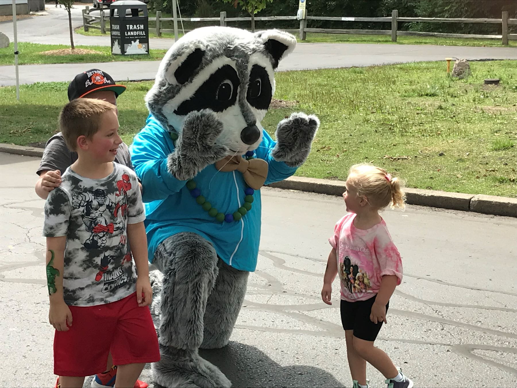 An EGLE Recycling Raccoons mascot greets children at the Detroit Zoo.