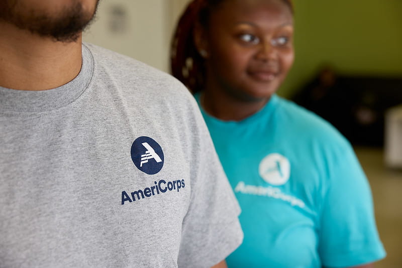 Two volunteers wearing t-shirts with Americorps logo.