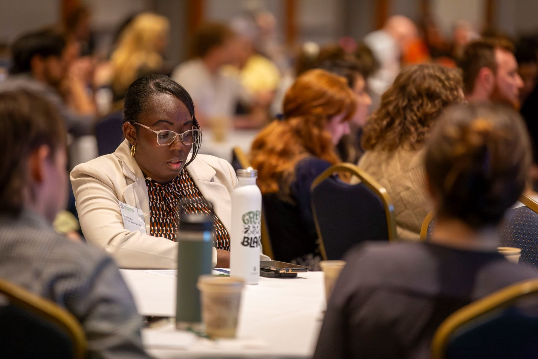 Attendee at the Environmental Justice conference in 2025 surrounded by other tables with attendees. 