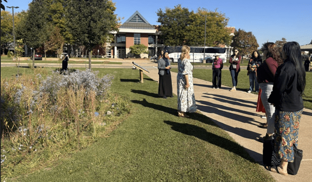 A small group of people standing outside next to a rain garden