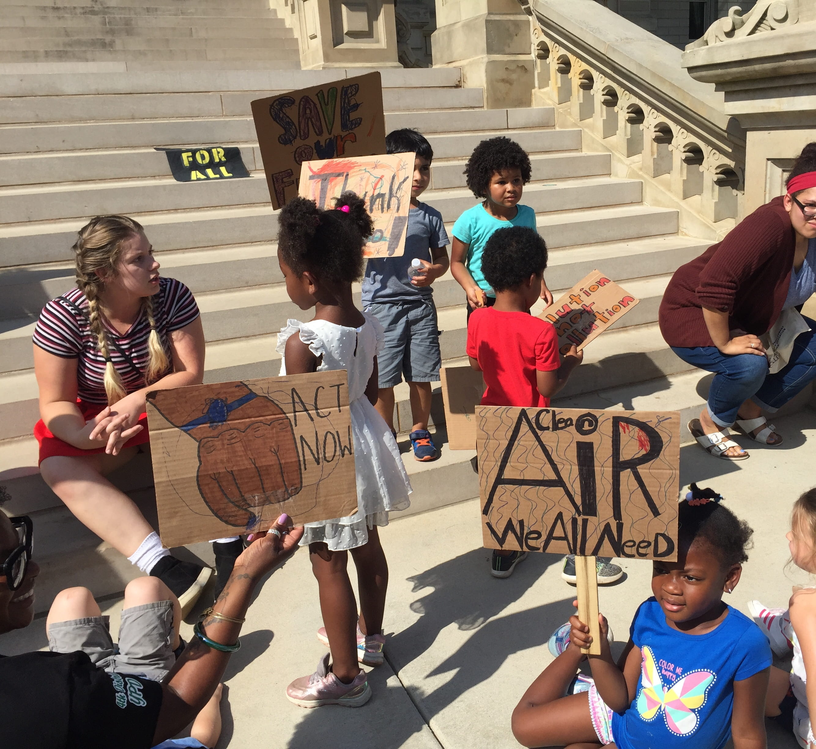 kids and woman on steps at demonstration for Environmental Justice