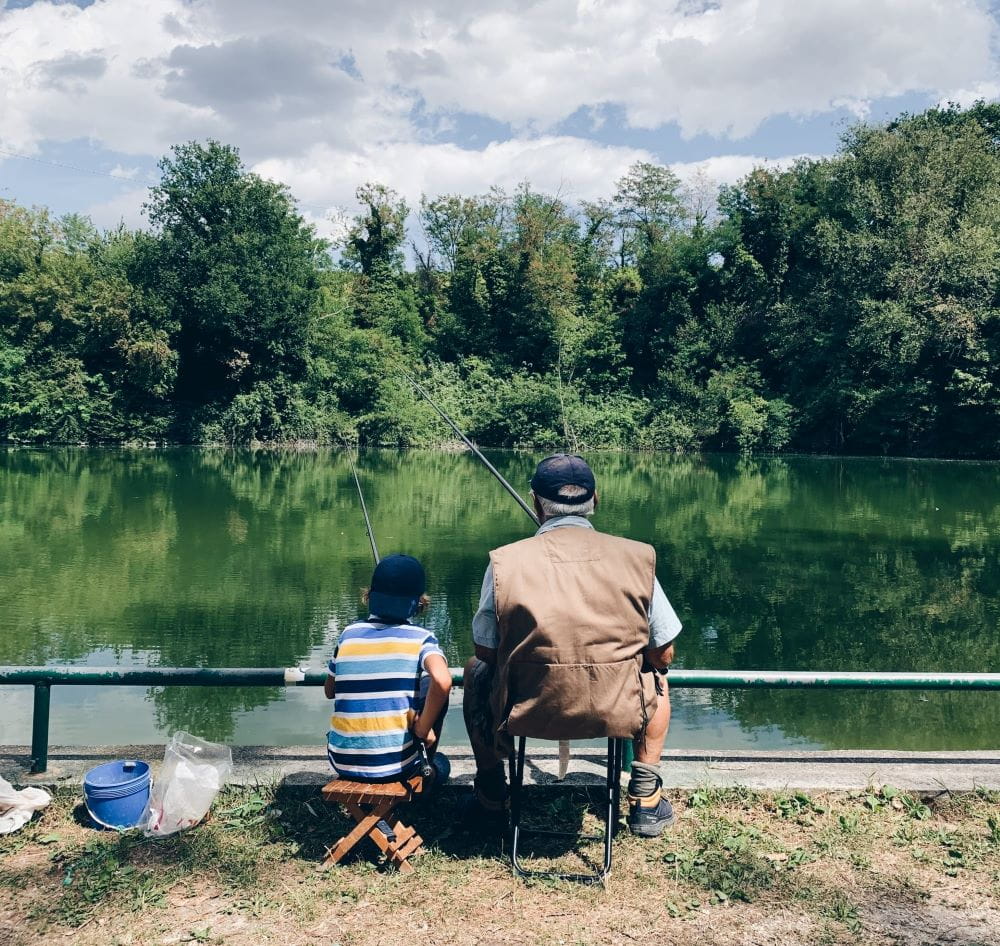 An adult and child sitting in chairs on a causeway, fishing