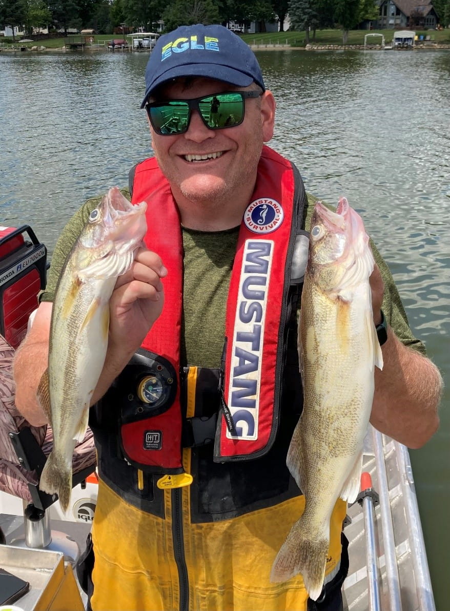 Aquatic biologist Mike McCauley holds two walleye collected from the Flint River in August 2022 for the Michigan Fish Contaminant Monitoring Program.
