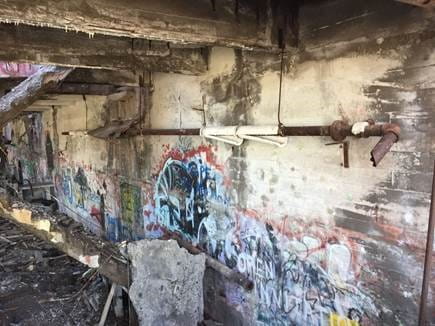 The above photo shows graffiti on the walls of the Quincy Mining Company- Mason stampmill, directly below a pipe wrapped in damaged, suspect asbestos pipe wrap material.