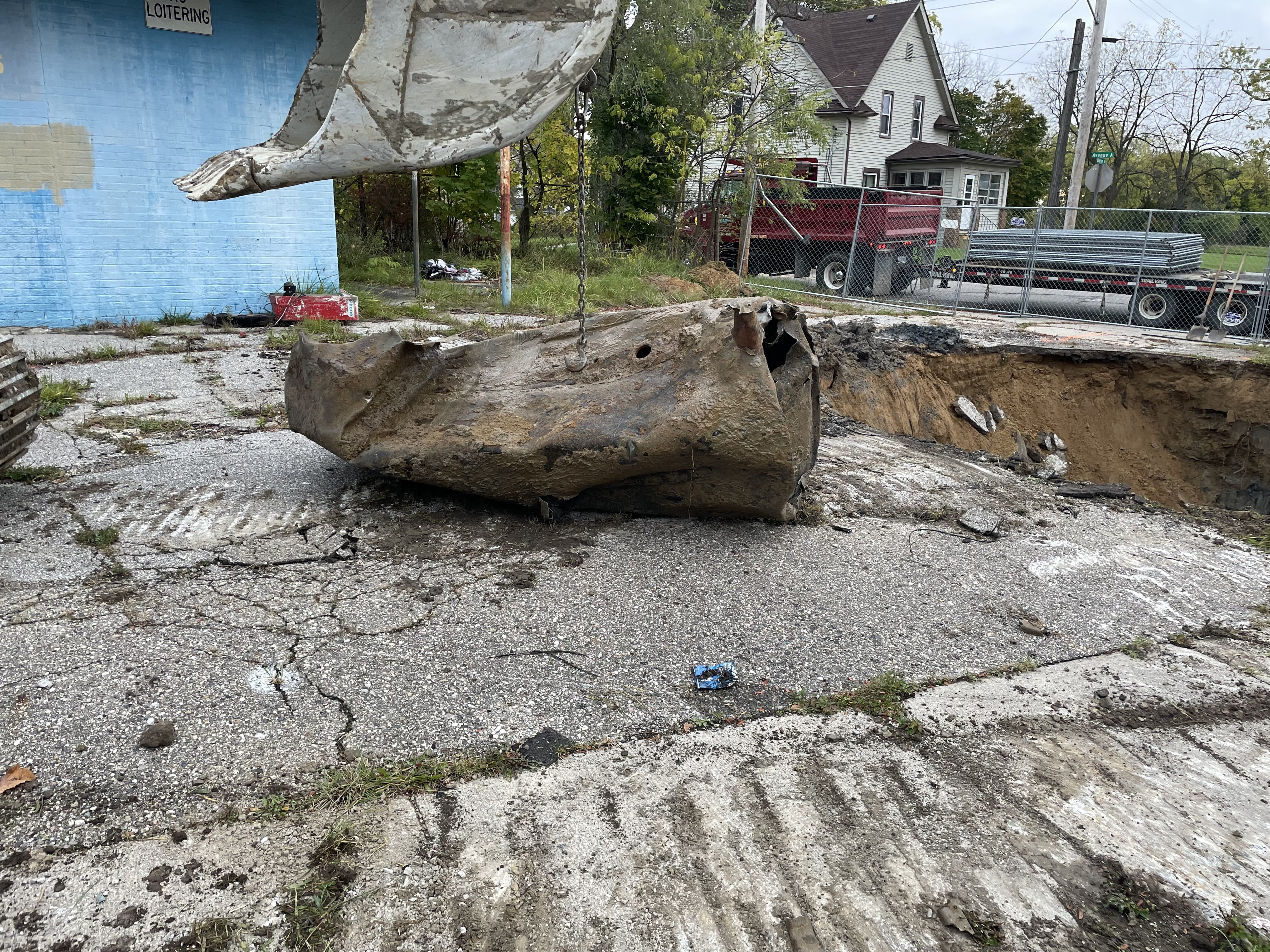 An excavator prepares to flatten a storage tank after it was removed from the ground.