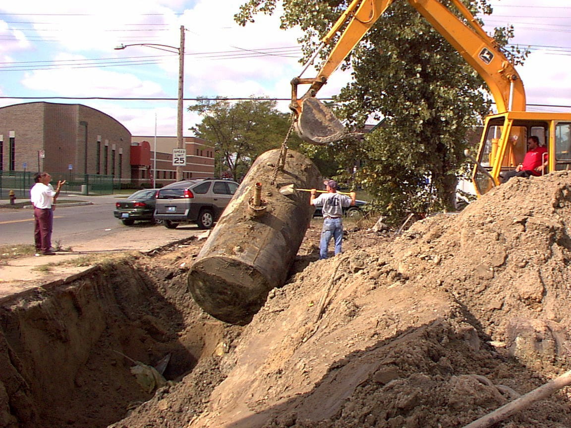 EGLE staff with construction equipment hauling underground storage tanks out of the ground at a contaminated property