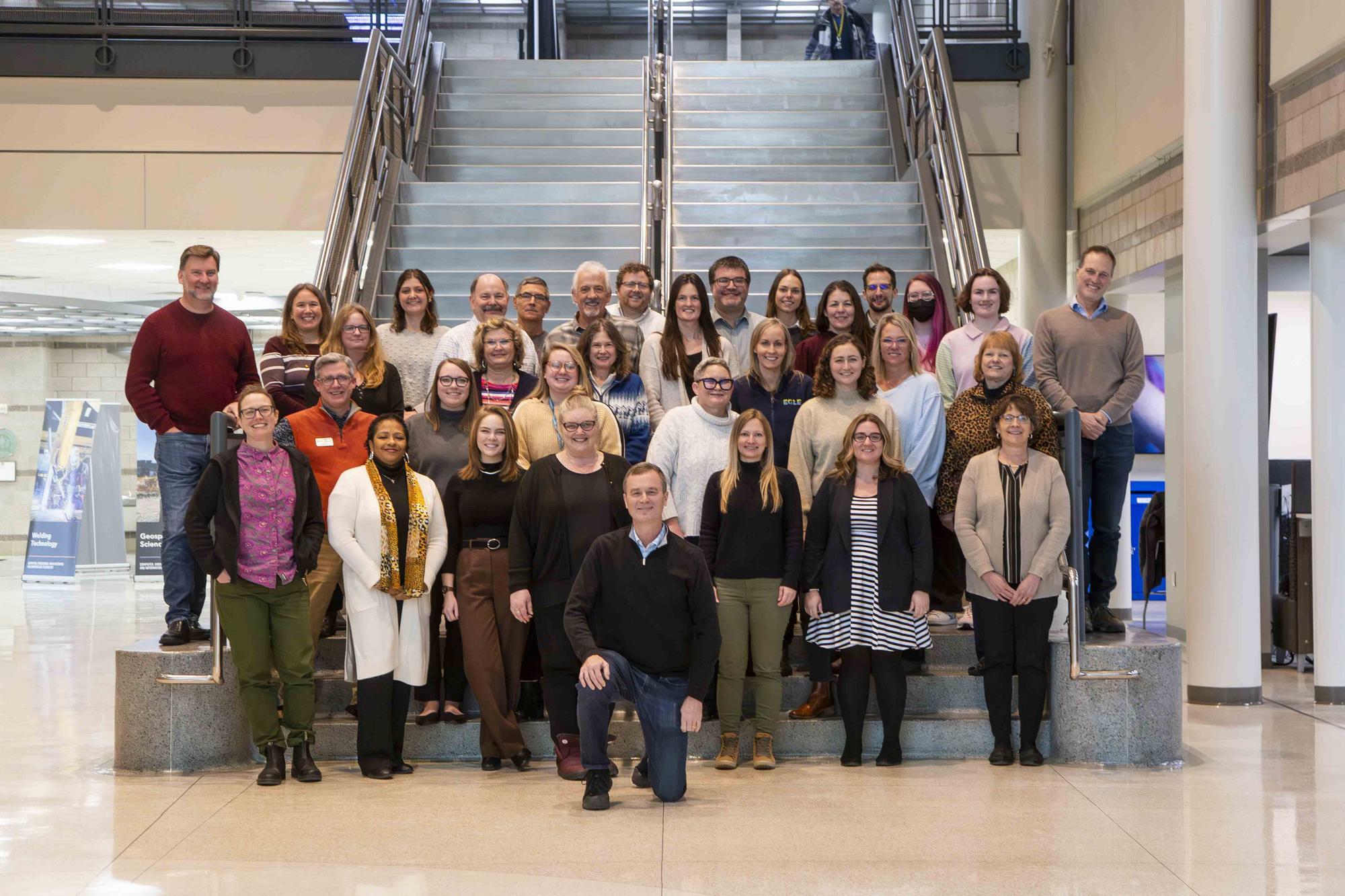The staff of the Executive Office standing at the bottom of the stairs in the Deborah A. Stabenow Building