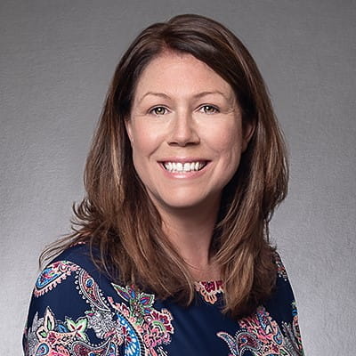Tracy Kecskemeti, wearing a patterned blouse and smiling