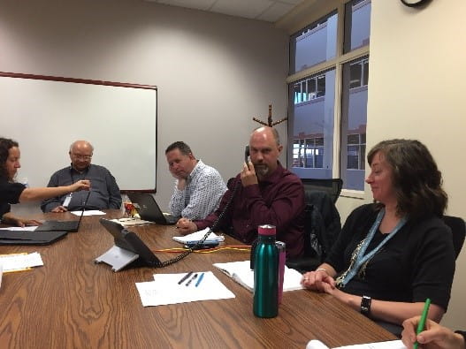 Meeting participants discuss details over a round table.