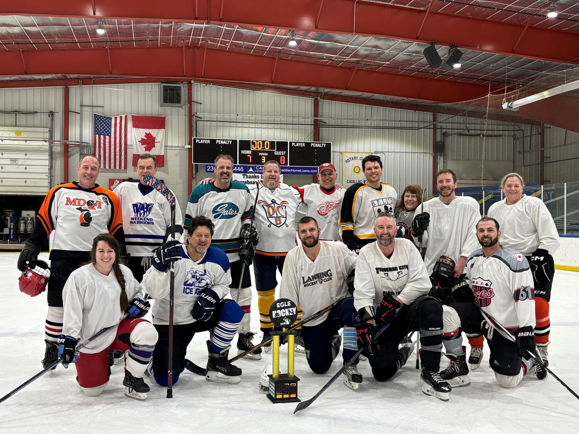 The 13 members of the EGLE hockey team – and one player for the DNR – pose with the trophy.
