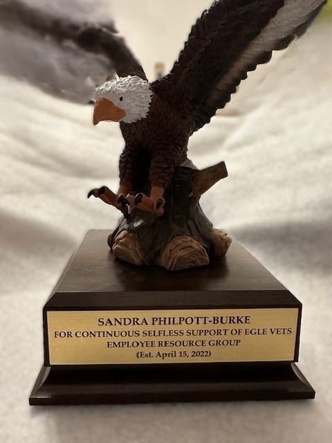 A carved wooden statue of a bald eagle with an engraved metal plate with award information on it