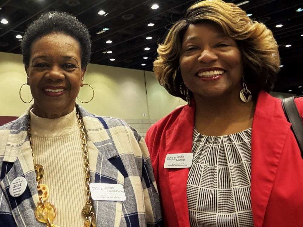 Two women dressed professionally standing close together for a photo and smiling
