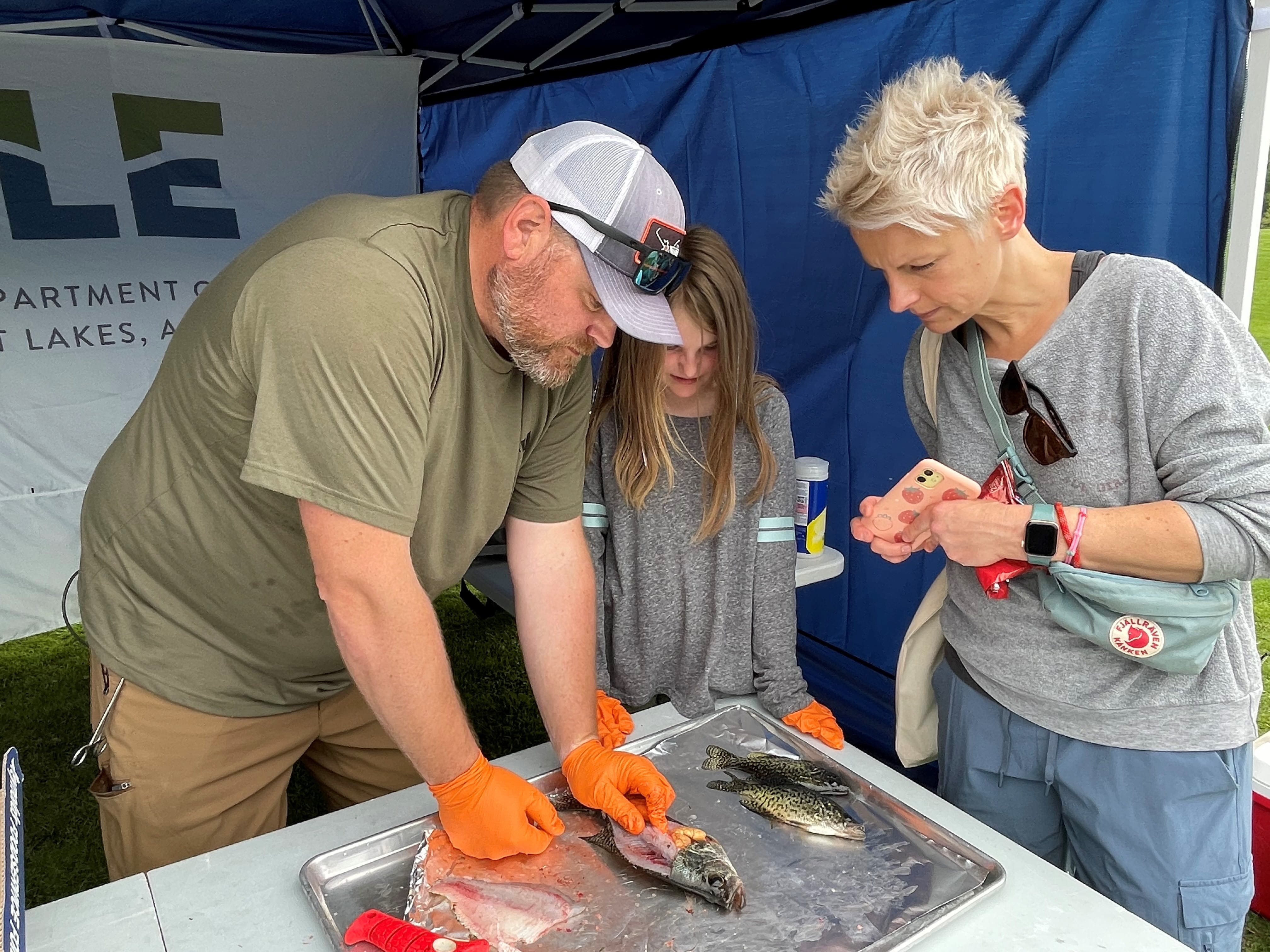 EGLE staff demonstrating the fish fillet process at the Hesse-Earl Youth Fishing Program at Hawk Island Park in 2023.