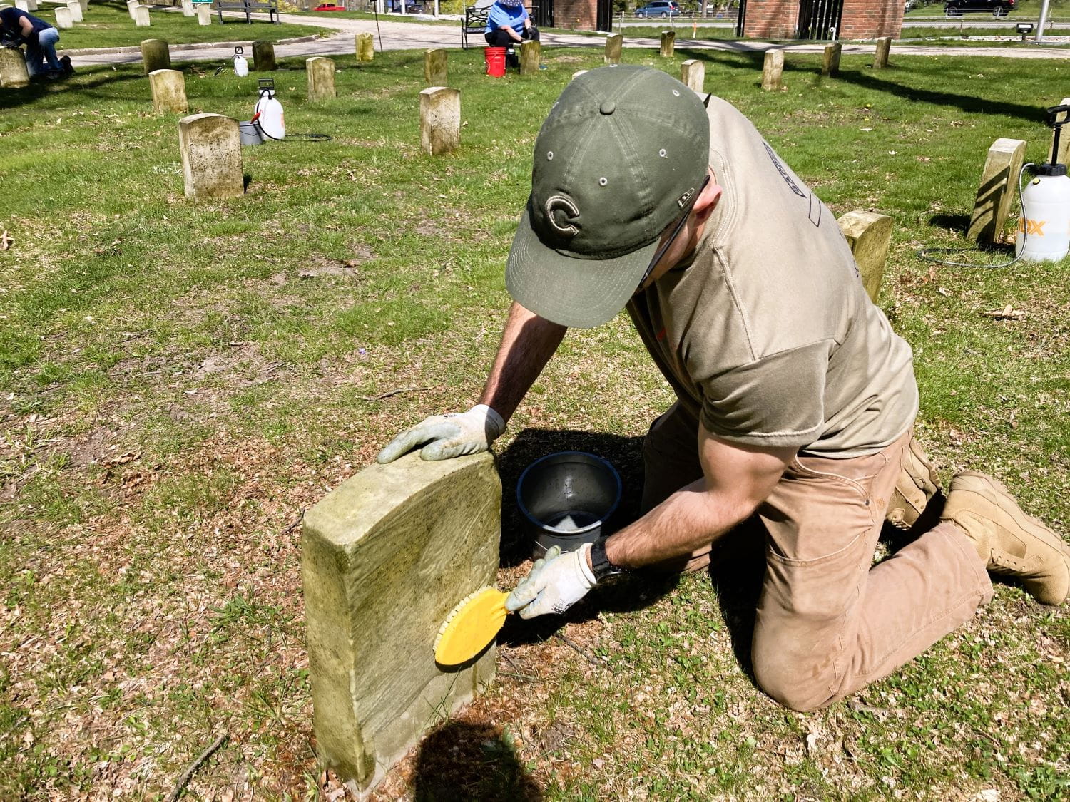 Adam Donne, of EGLE, cleans a headstone at the veterans' cemetery in Grand Rapids. 