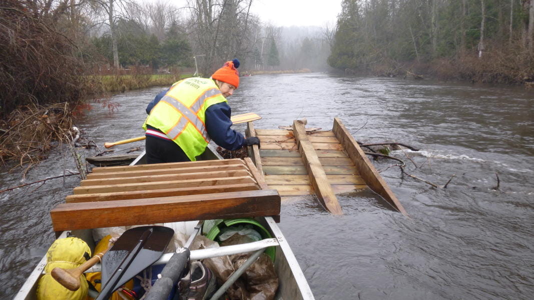 MI Corps volunteer in a canoe cleans up a river.