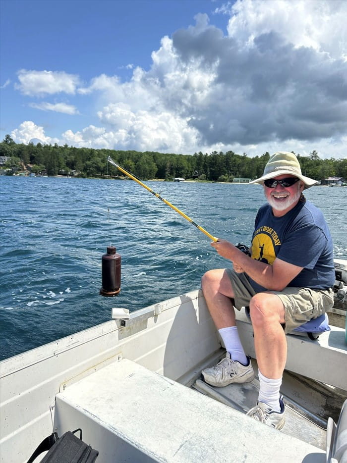 Person in boat smiling taking water sample of lake. 