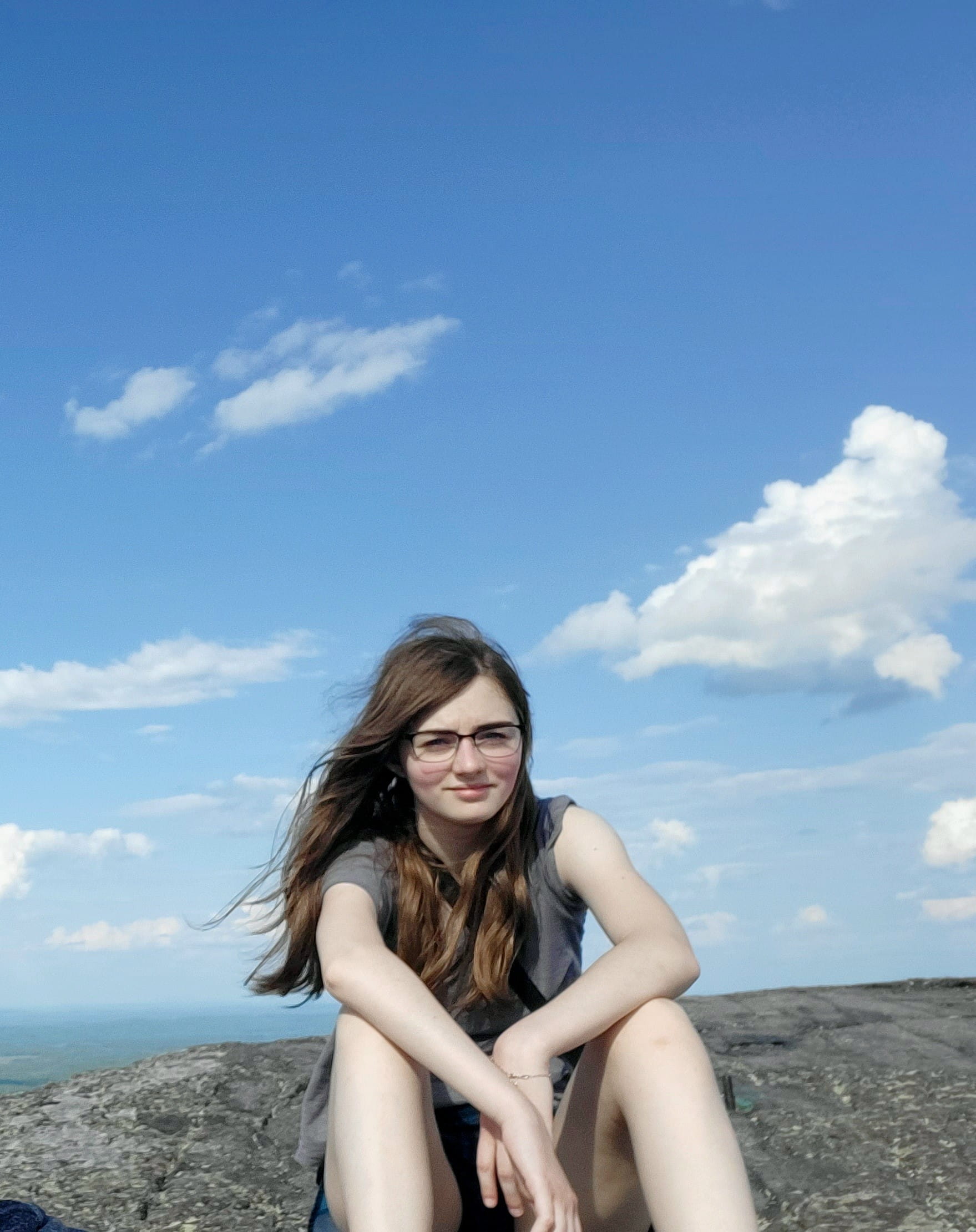 Isabelle Clark,17-year-old daughter of Alexandra Clark, Enforcement Section Manager, Materials Management Division., sitting on large rock.