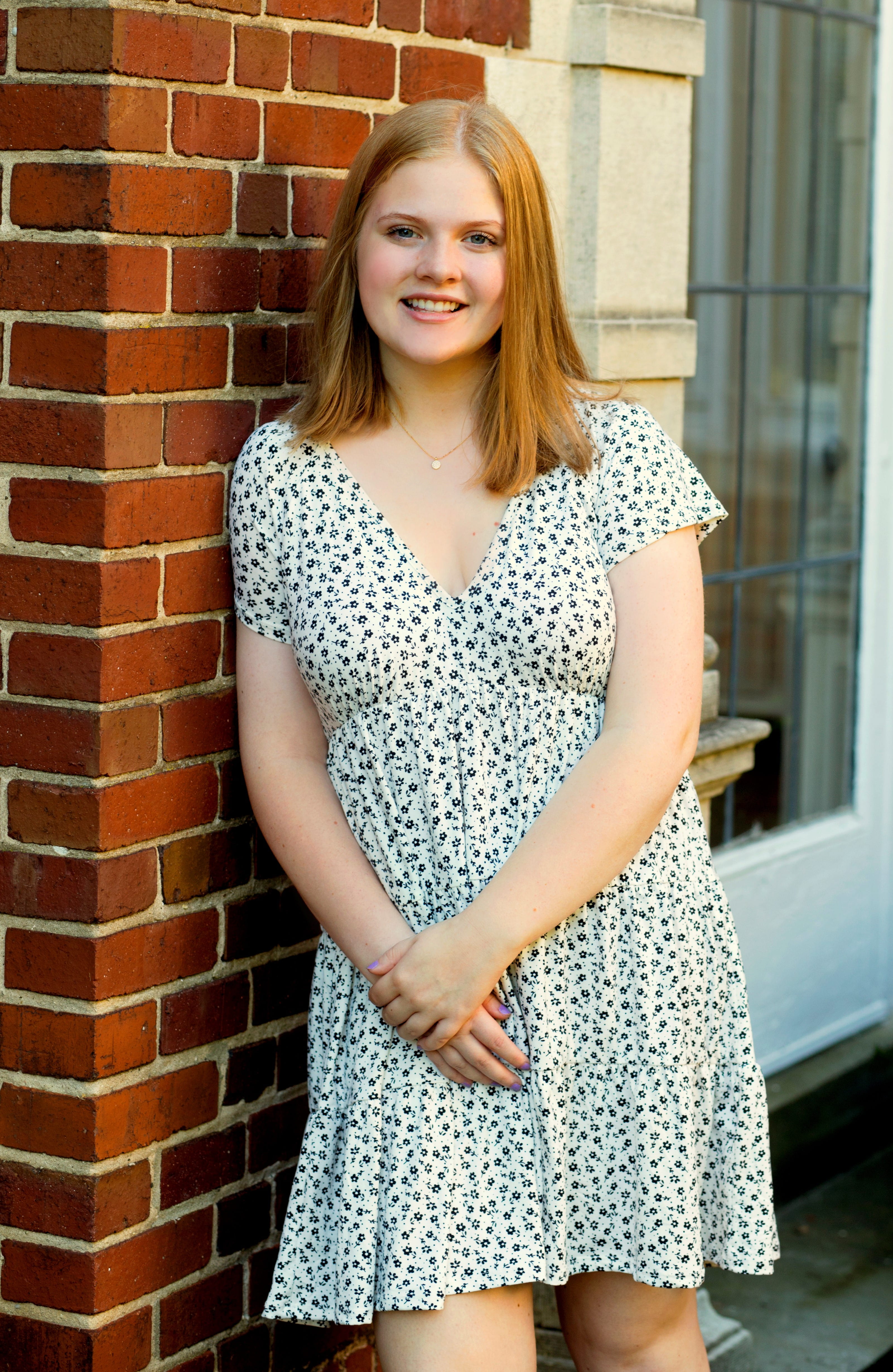Katie Philipps, daughter of Jennifer Philipps, leaning against red brick wall.