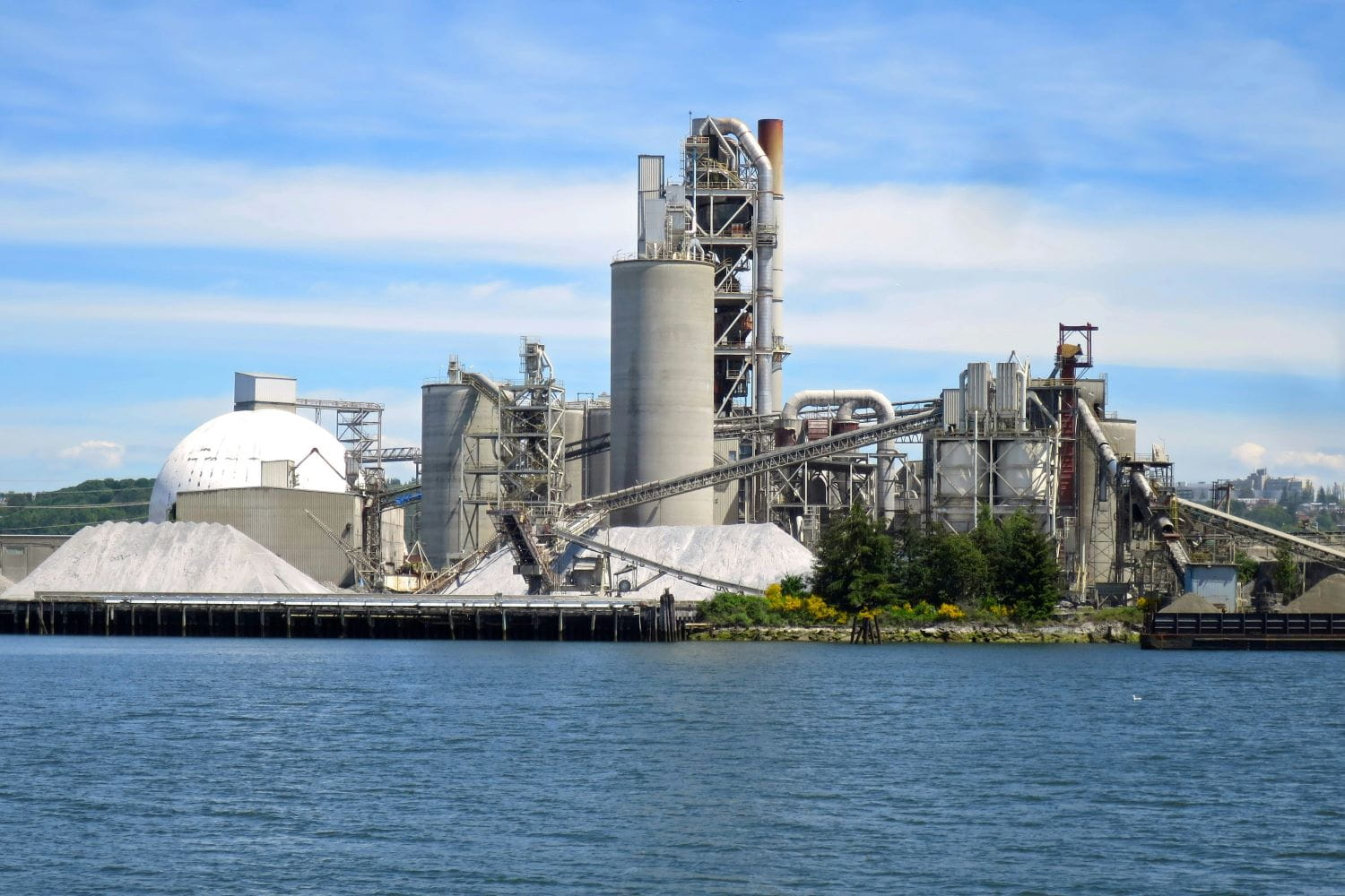 A large industrial cement manufacturing plant located on a lakeshore