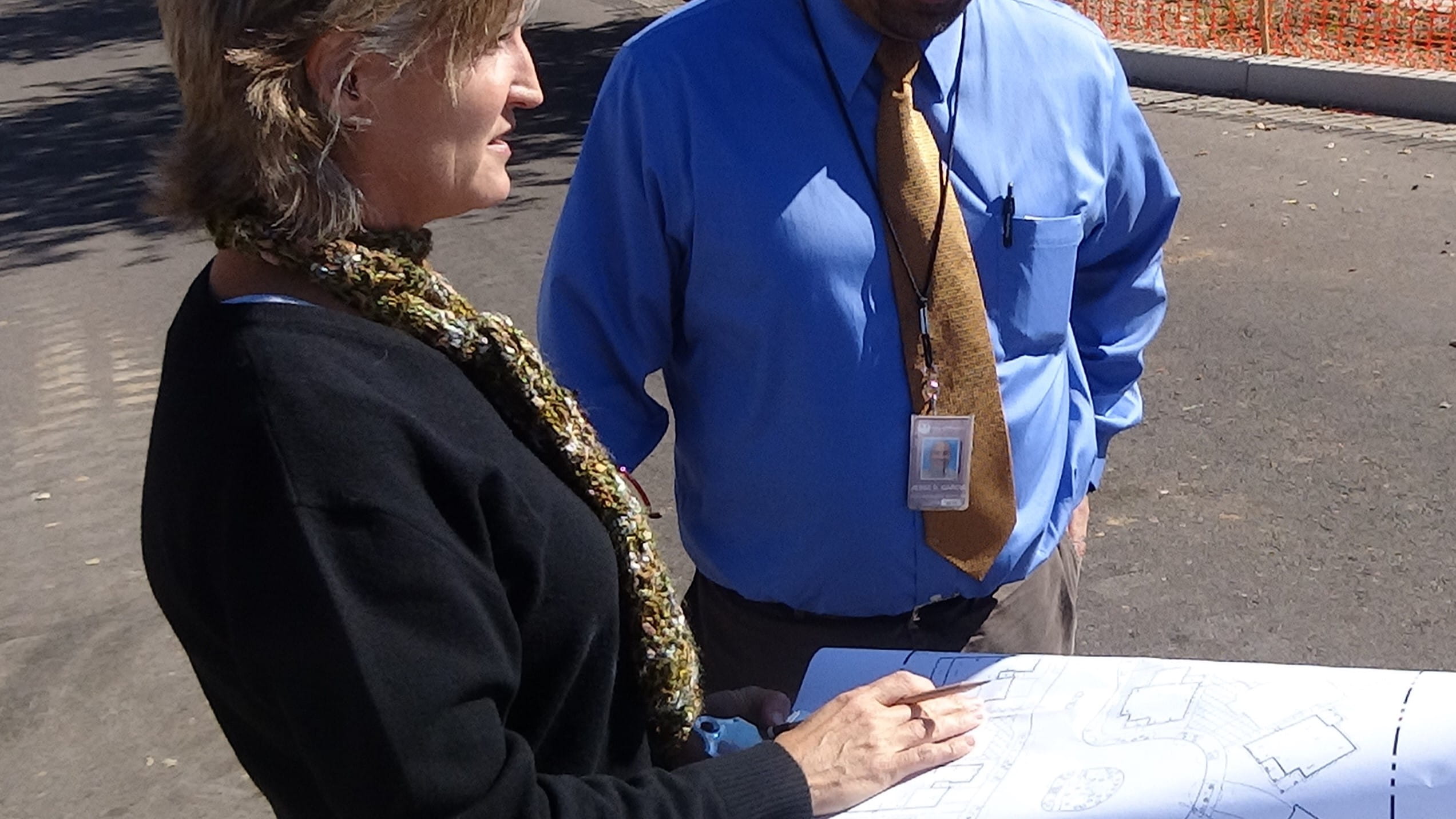 Two contractors wearing badges review plans 