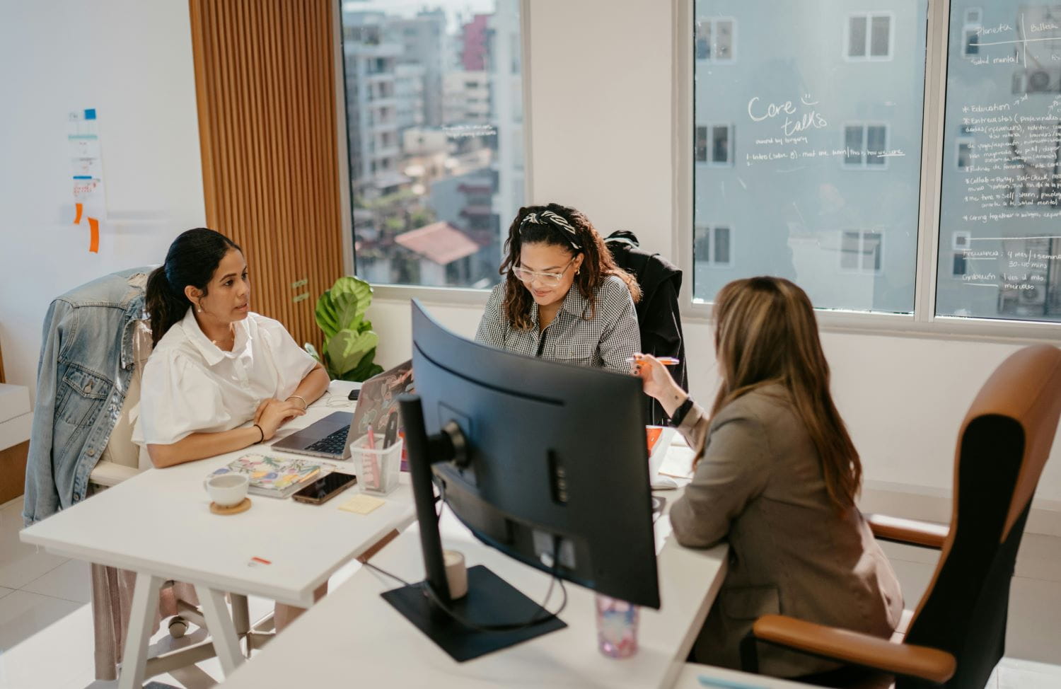 An office space with three professional working women at a desk, collaborating