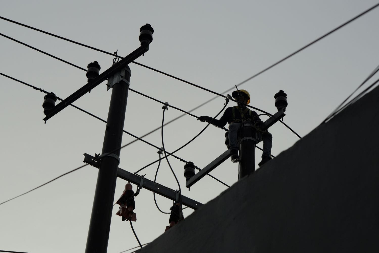 A utility worker on a telephone pole, silhouetted