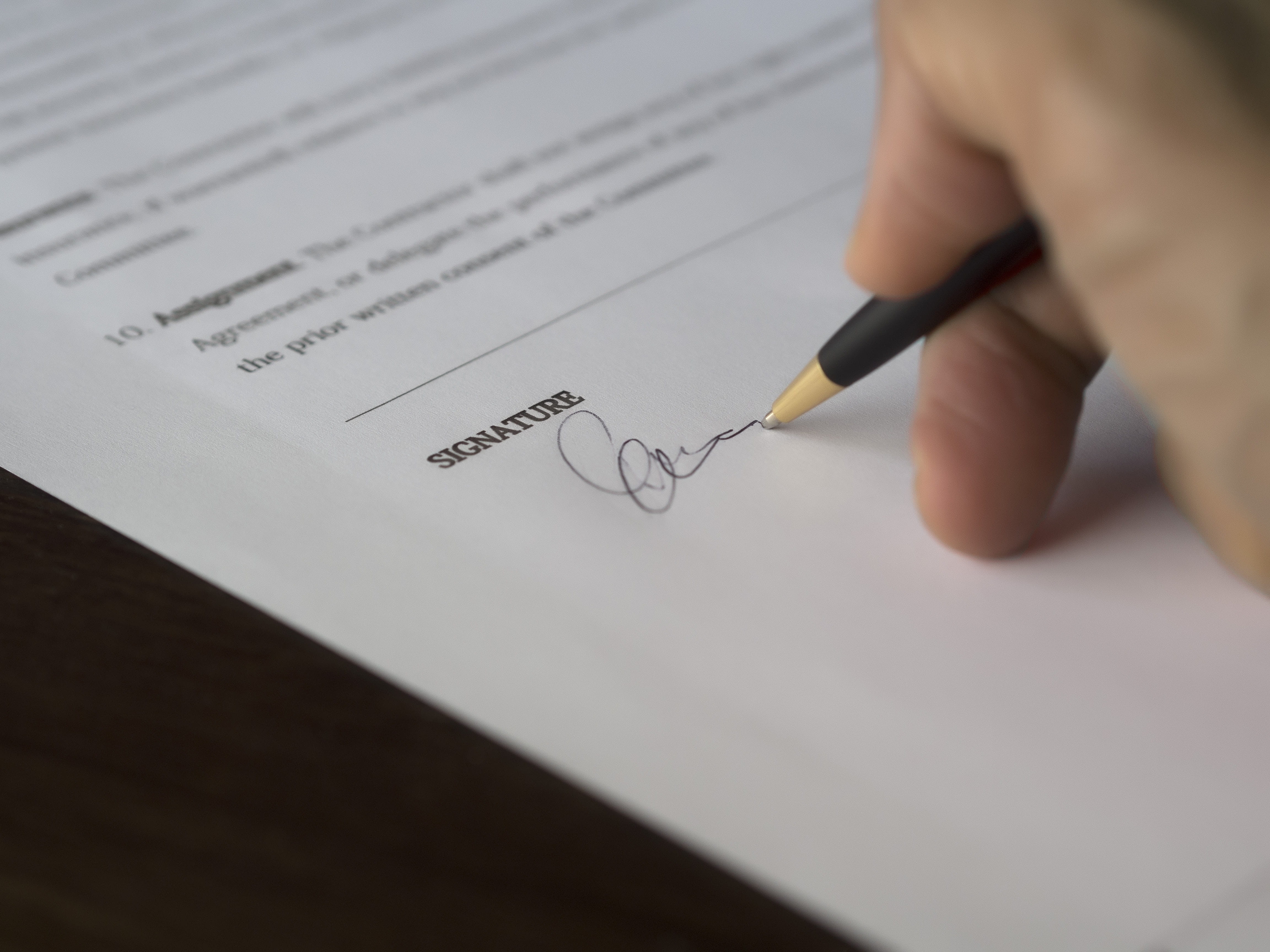 A hand holding a pen and signing a document