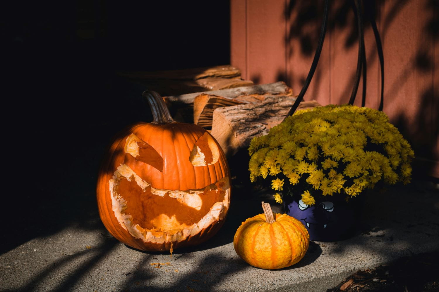 A carved pumpkin that looks nibbled on by squirrels on a porch next to a smaller pumpkin