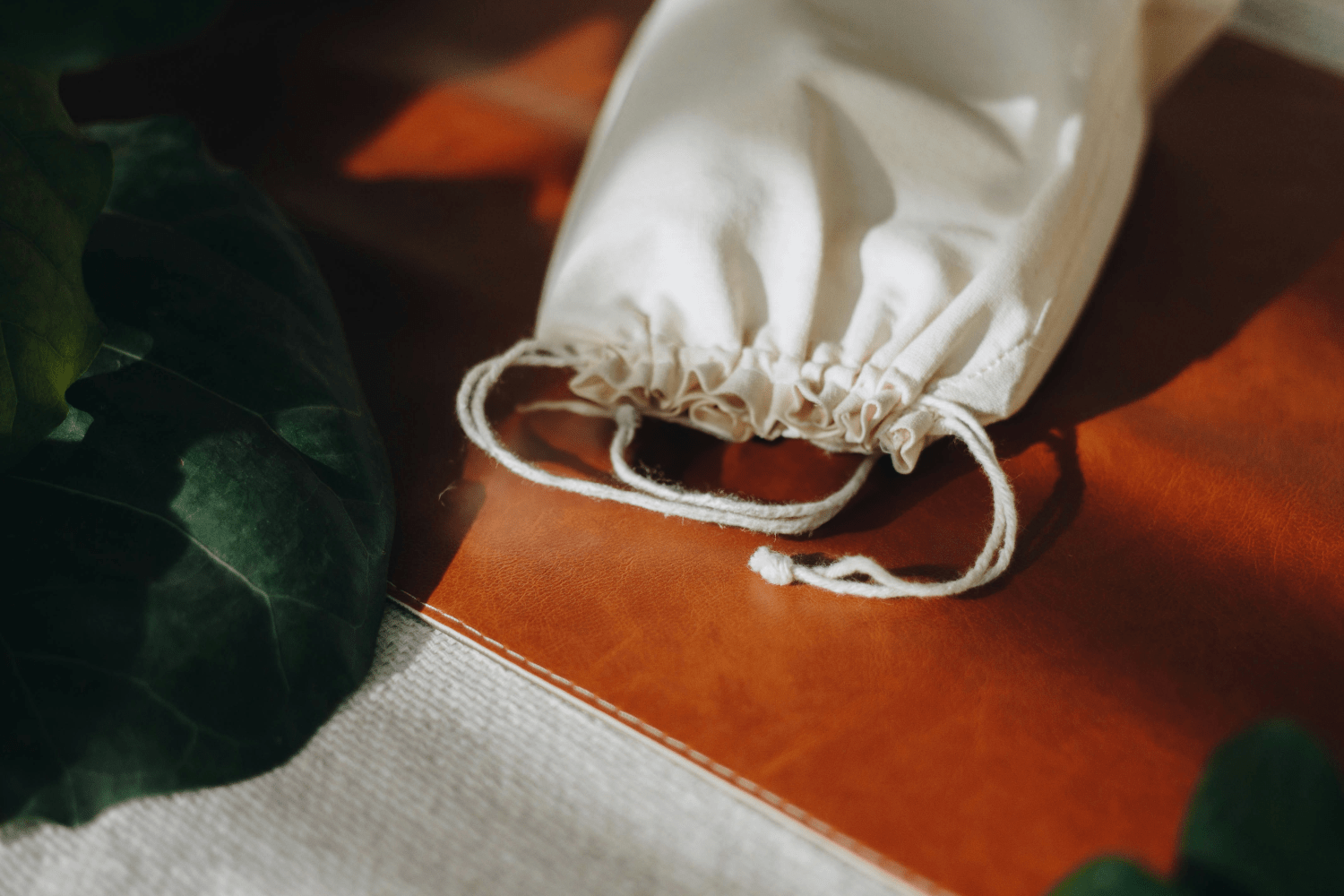 A plain white cloth gift bag resting on a brown tabletop