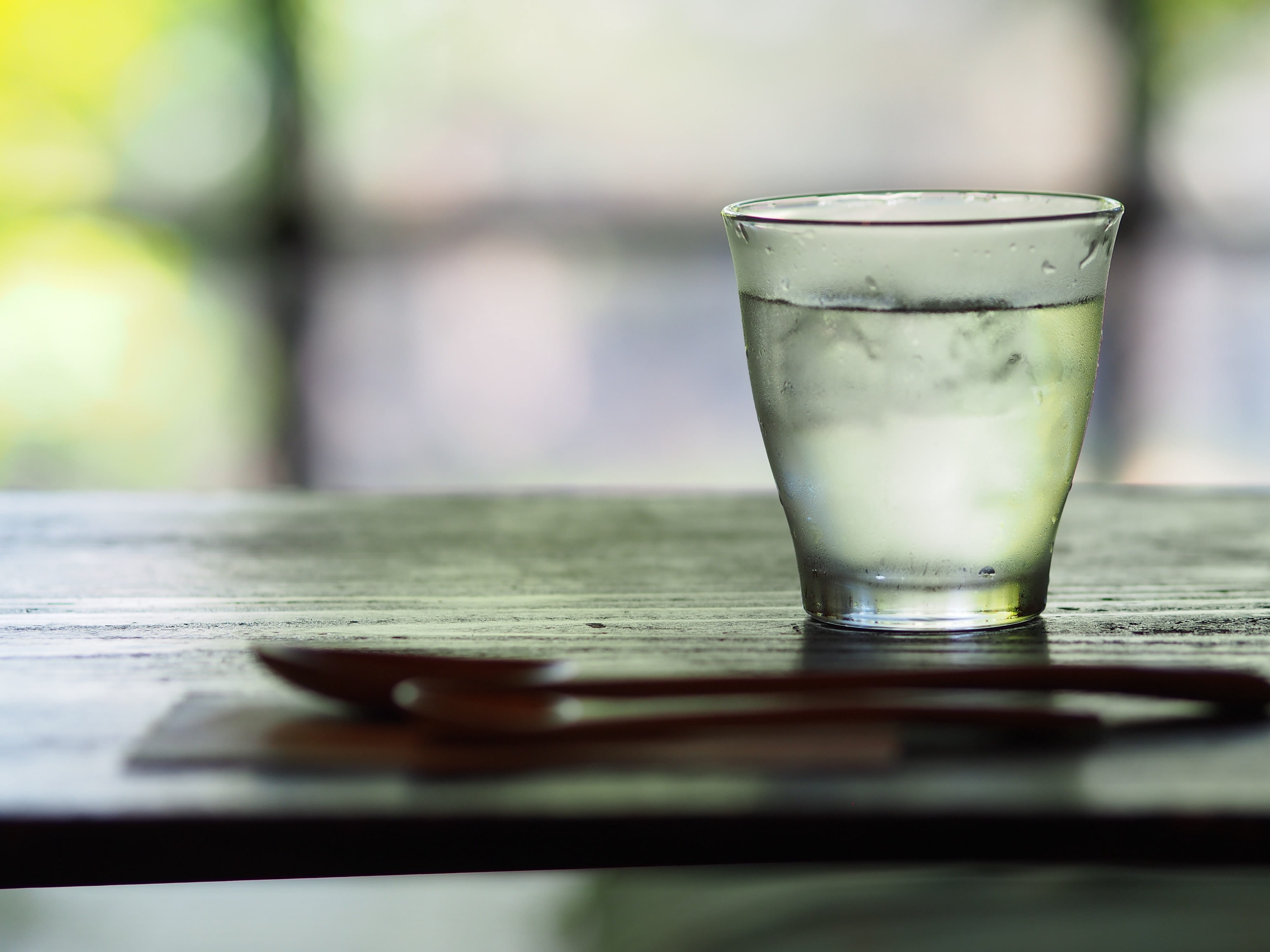 A side view of a glass of clear water sitting on a wooden table
