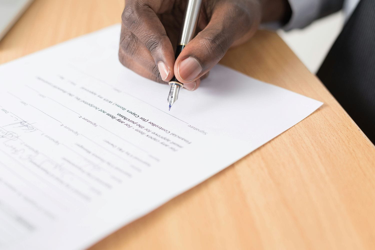 An African-American man signing a document on a desk