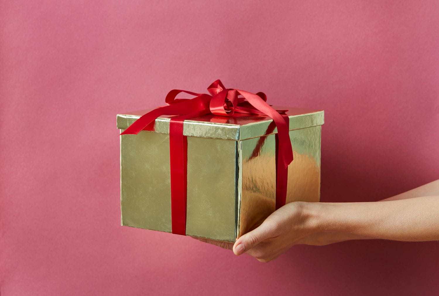 A metallic gold cardboard gift box with red ribbon
