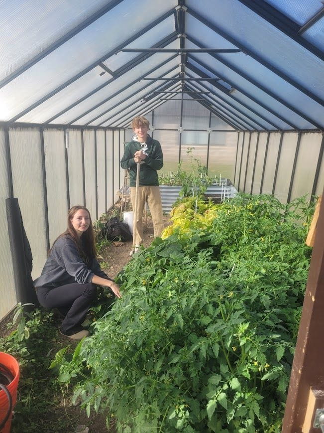Two students working in a greenhouse on a Mason County Eastern Schools Greenhouse Revitalization Project.