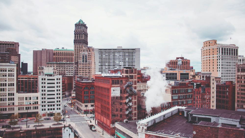 Buildings in the heart of downtown Detroit with a grey sky and smoke coming from some of the buildings