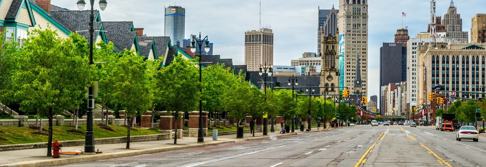 Detroit skyline in the background with a tree-lined street in the foreground