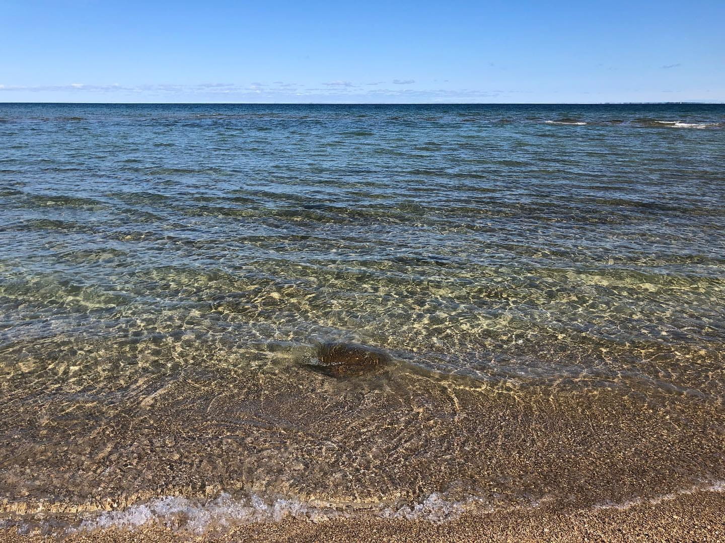 Crystal clear water of Lake Michigan washing up on a pebbled shoreline at Wilderness State Park on a beautiful summer day