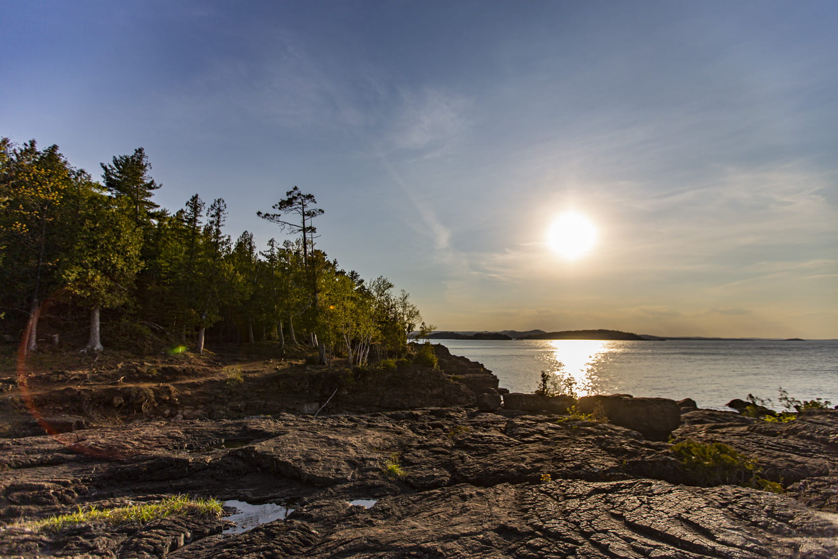 A warm summer sun shining over a rocky outcrop at Pictured Rocks National Lakeshore. Lake Superior is in the background
