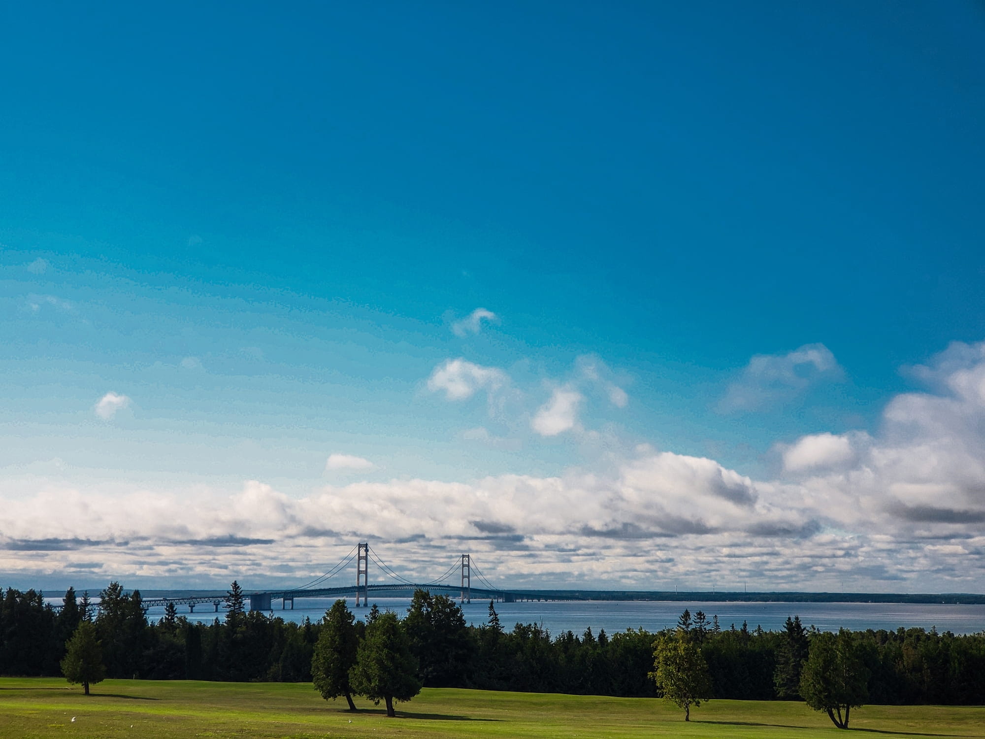 The Mackinac Bridge far in the distance, with a lush green golf course in the foreground
