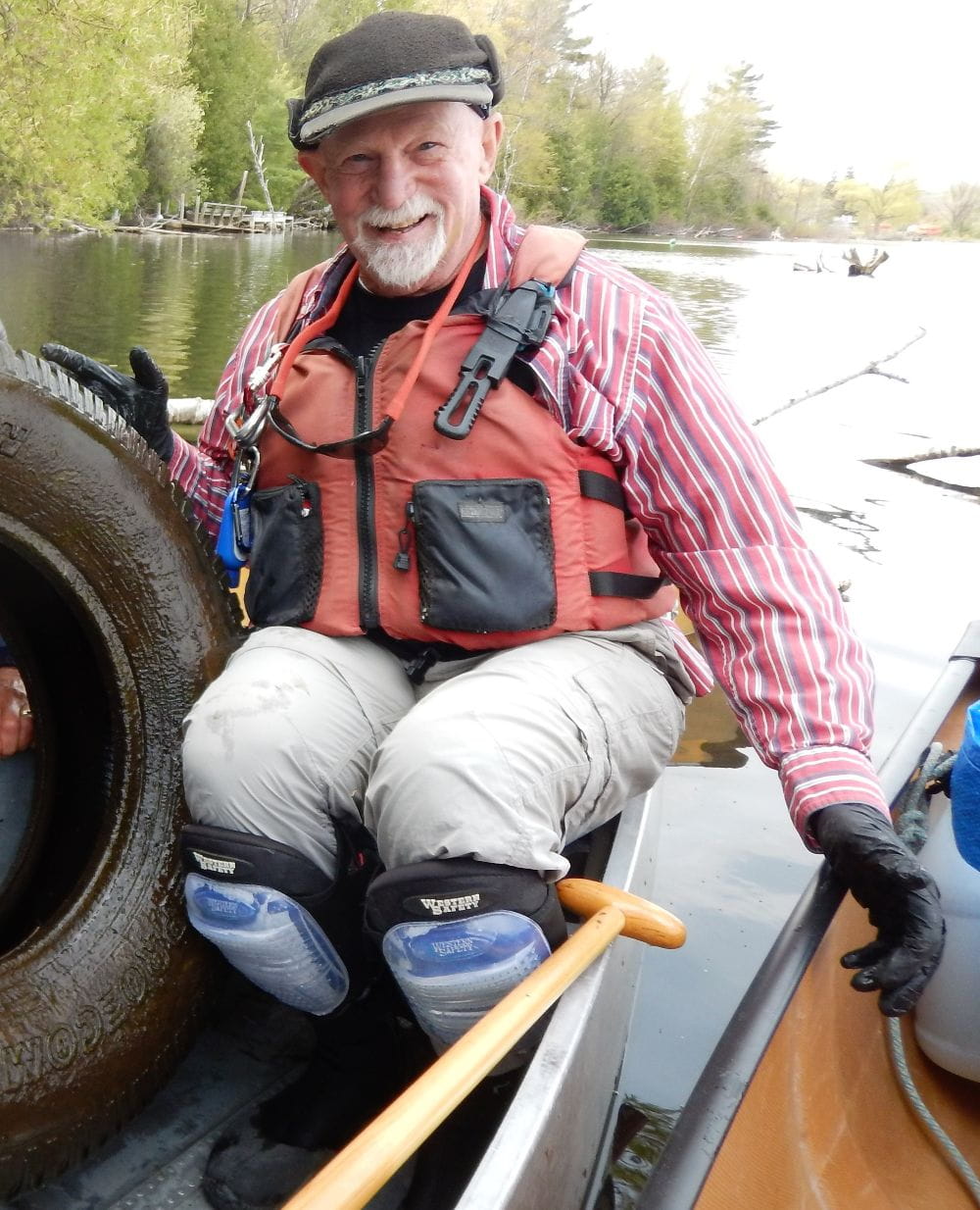 Norm Fred, founder of Boardman River Clean Sweep, sits in a canoe with a tire removed from the Boardman River at a river cleanup event funded by MiCorps. Credit: Boardman River Clean Sweep.