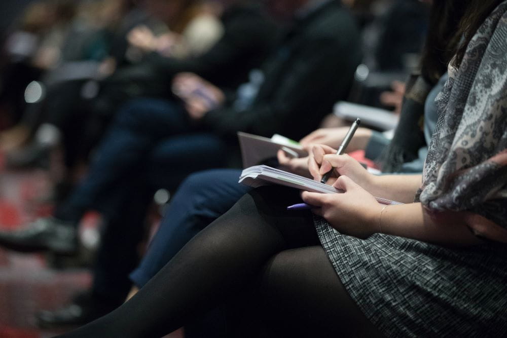 An audience member taking notes