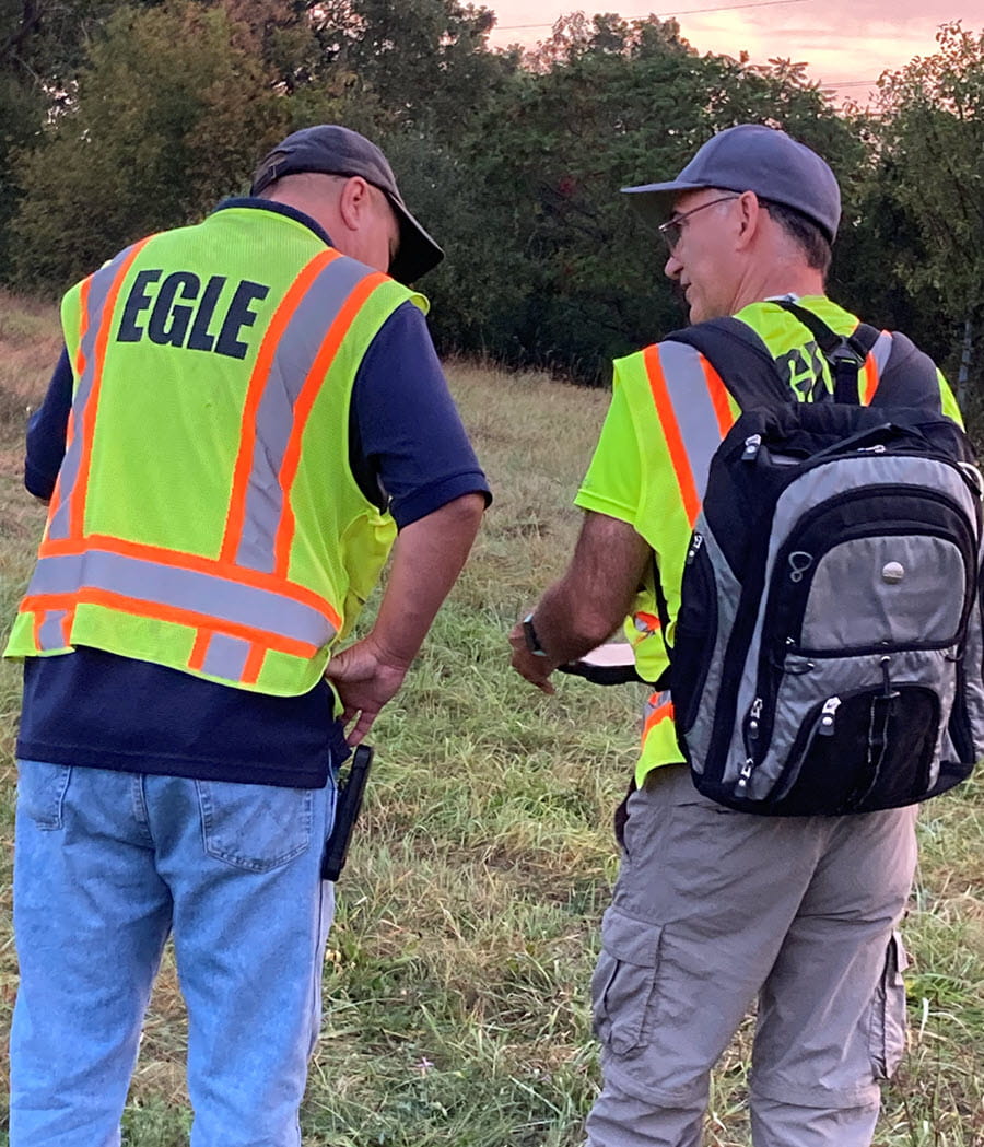 Two EGLE Staff in safety vests talk in field