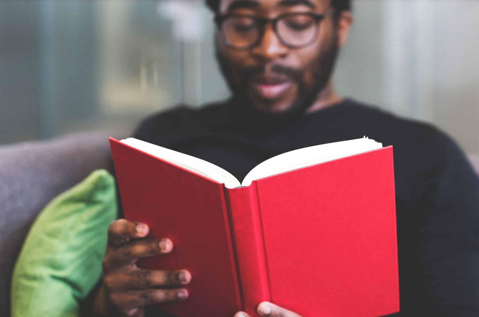 Man reading book with red cover.