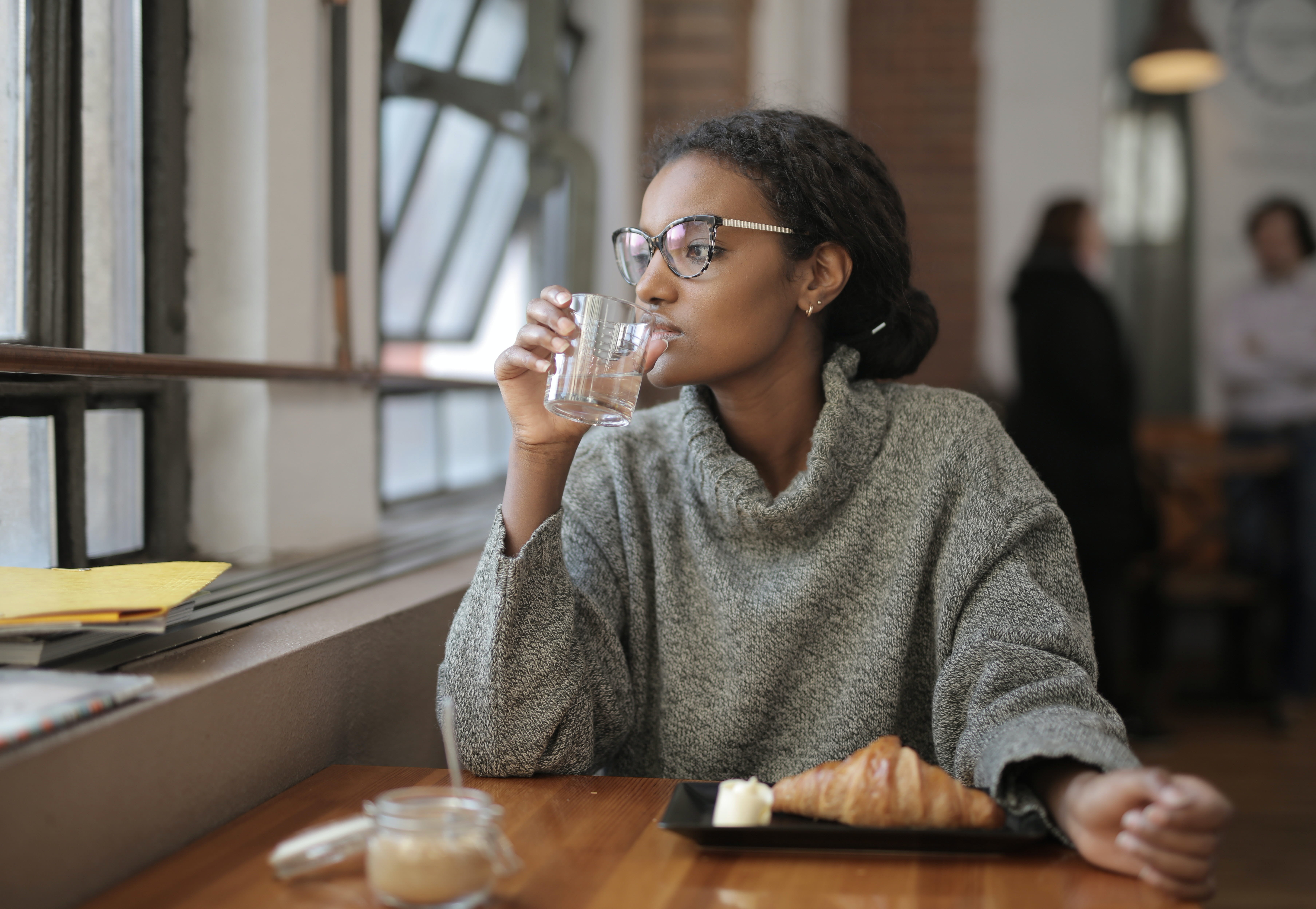 A young woman at a cafe drinking a glass of water